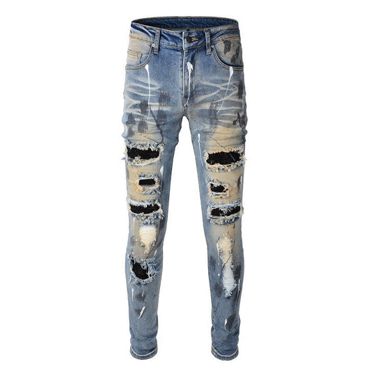 Jeans azules para hombre con parches negros, pintura desgastada y detalles rotos 523