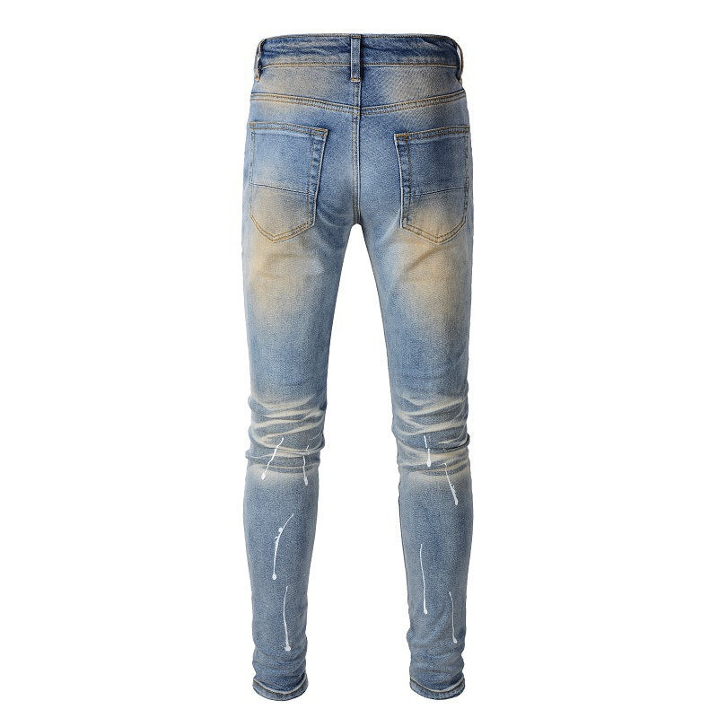 Jeans azules para hombre con parches negros, pintura desgastada y detalles rotos 523