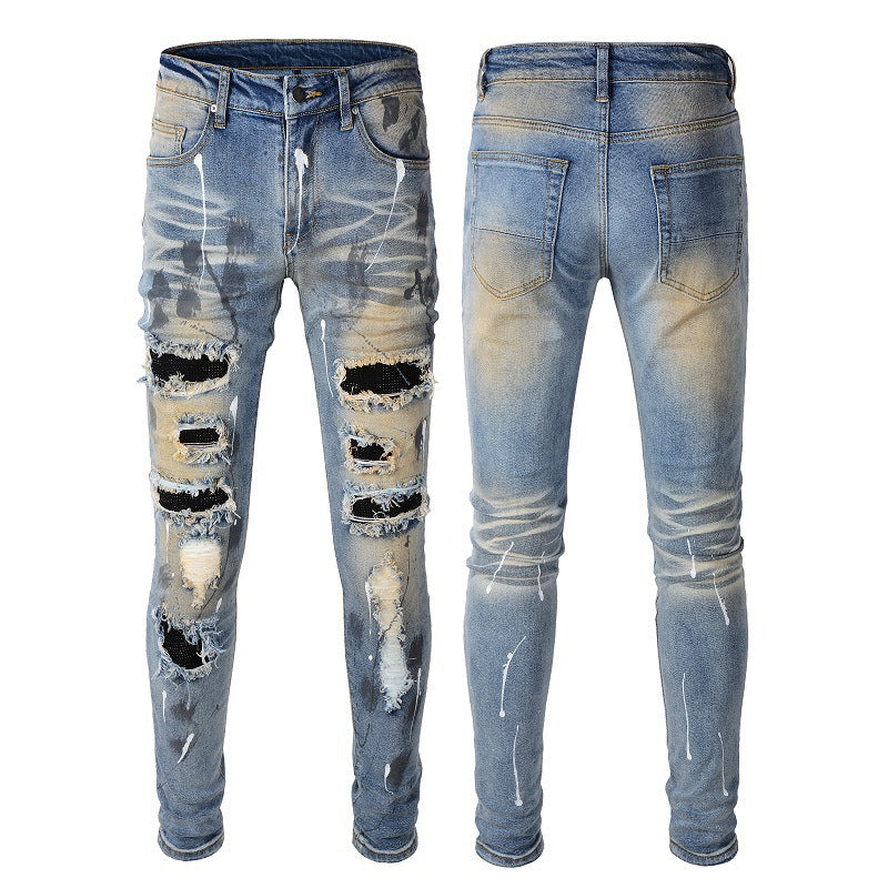 Jeans azules para hombre con parches negros, pintura desgastada y detalles rotos 523